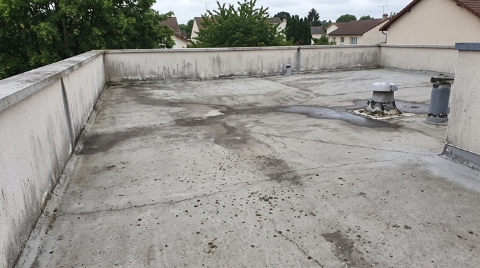 Toit plat avec fissures et traces d'humidité à traiter